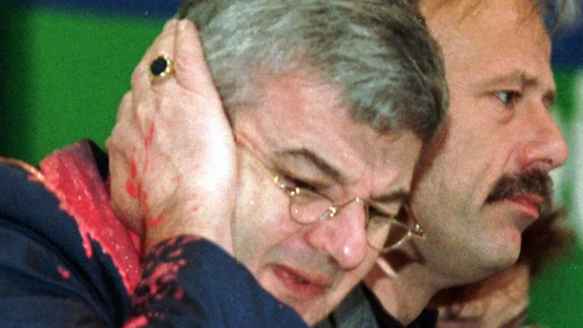 Von einem Farbbeutel getroffen, faßt sich Bundesaußenminister Joschka Fischer am 13.5.1999 auf dem Sonderparteitag der Grünen in Bielefeld erschrocken ans Ohr, rechts sitzen Bundesumweltminister Jürgen Trittin und die verteidigungspoltische Sprecherin der Grünen, Angelika Beer. Fischer war von einem Demonstranten mit einem Farbbeutel beworfen worden und erlitt dabei leichte Risse im Trommelfell. Er ließ sich deswegen kurz in einem Krankenhaus behandeln. Der Unbekannte hatte Fischer als "Kriegshetzer" beschimmpft und den roten Farbbeutel auf den Minister geworfen, als er den Parteitag auf dem Präsidiums-Podium verfolgte. [dpabilderarchiv]