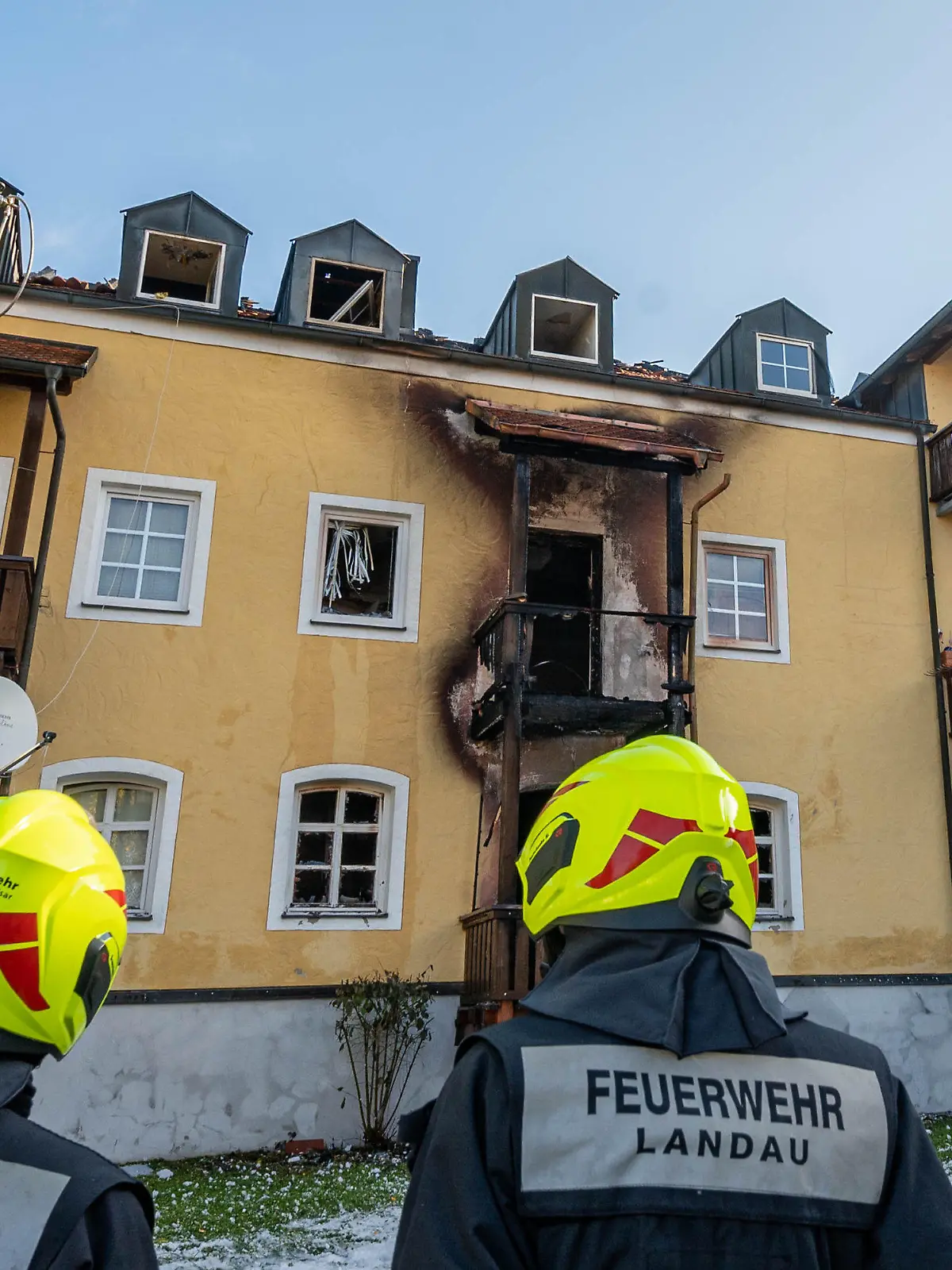 23.10.2021, Bayern, Reisbach: Feuerwehrmänner stehen vor einem ausgebrannten Mehrfamilienhaus. Drei Frauen und ein frühgeborenes Baby sind in dem Haus bei einem Brand ums Leben gekommen. Foto: Armin Weigel/dpa +++ dpa-Bildfunk +++