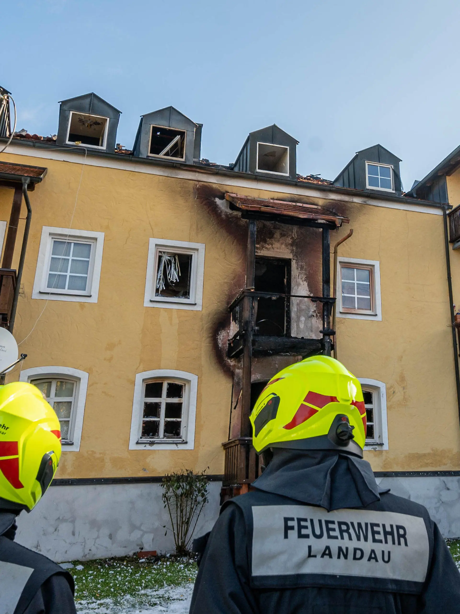 23.10.2021, Bayern, Reisbach: Feuerwehrmänner stehen vor einem ausgebrannten Mehrfamilienhaus. Drei Frauen und ein frühgeborenes Baby sind in dem Haus bei einem Brand ums Leben gekommen. Foto: Armin Weigel/dpa +++ dpa-Bildfunk +++