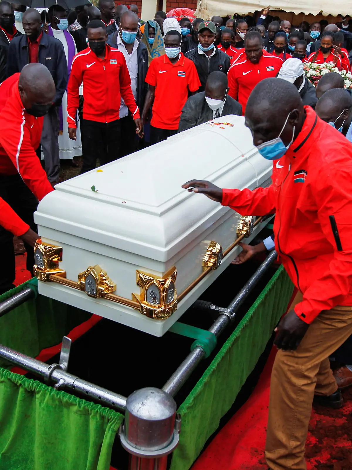 Kenyan athletes and family members place the coffin of the long-distance runner Agnes Tirop on her grave for burial at Kapnyamisa village, Nandi county, Kenya, October 23, 2021. REUTERS/Monicah Mwangi