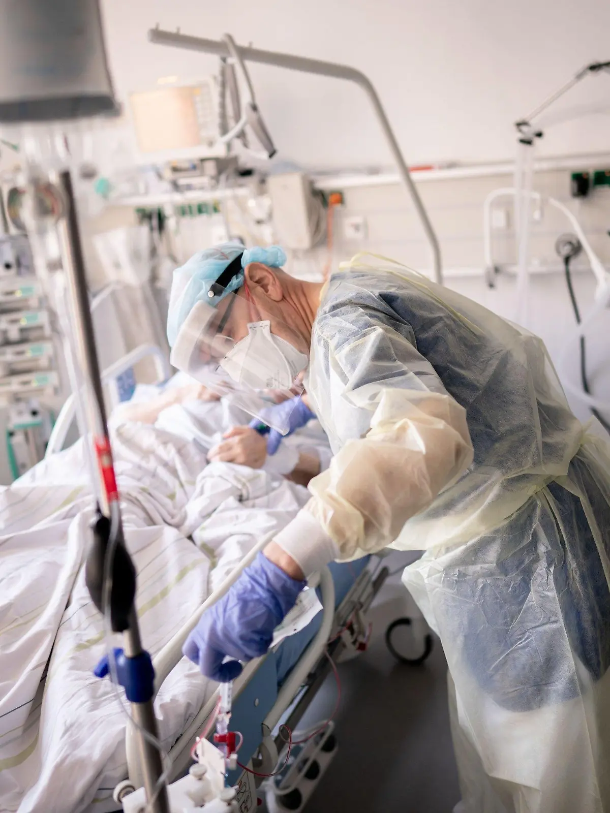 ARCHIV - 20.04.2021, Berlin: Ein Intensivpfleger arbeitet auf der Intensivstation eines Krankenhauses an einer an Covid-19 erkrankten Patientin. Die Gefahr einer Corona-Infektion ist für immer mehr Menschen in Deutschland im Verlauf der Pandemie nähergerückt. So haben im vergangenen März bereits sieben von zehn Menschen mindestens einen Menschen aus dem engeren Umfeld gekannt, der eine Coronainfektion erlitten hatte.    (zu dpa "Corona-Gefahr rückte für die Menschen in Deutschland immer näher") Foto: Kay Nietfeld/dpa +++ dpa-Bildfunk +++