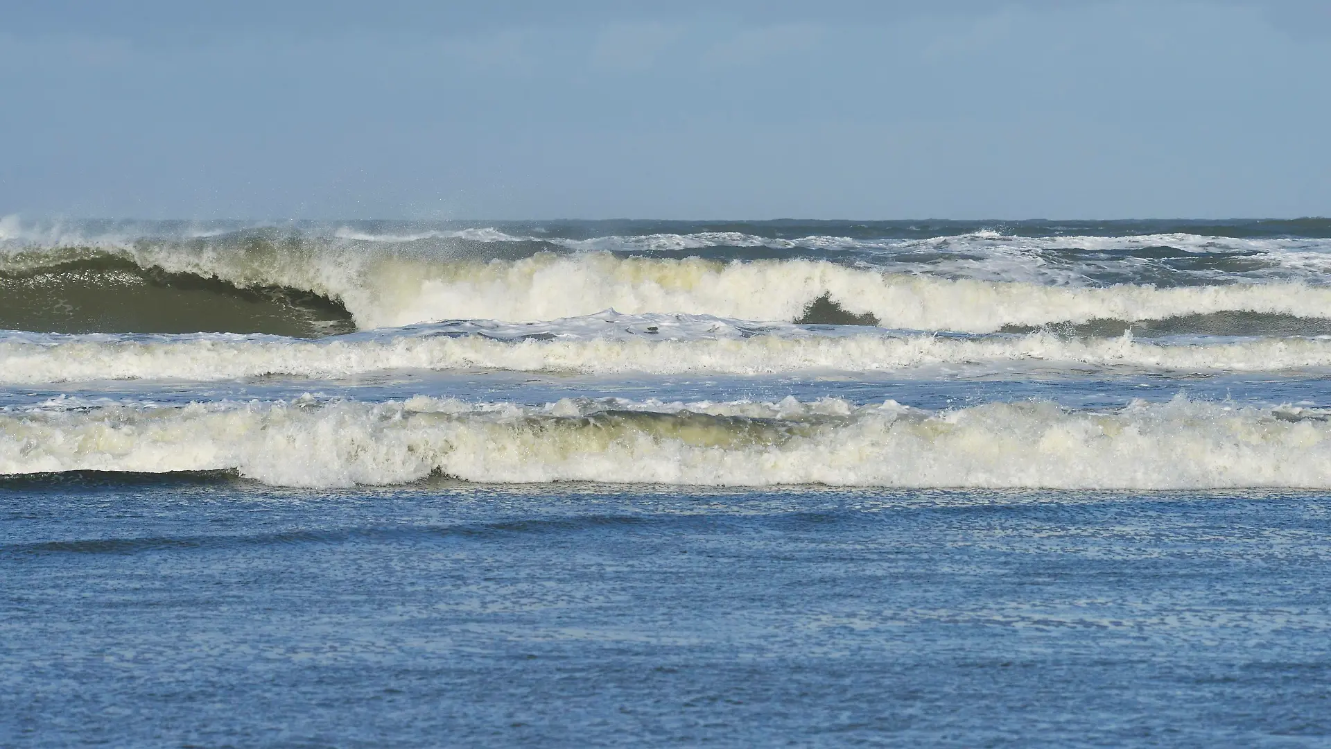 Wellen mit weißer Gischt von der stürmischen Nordsee an der Küste der Insel Langeoog, 24.10.2013