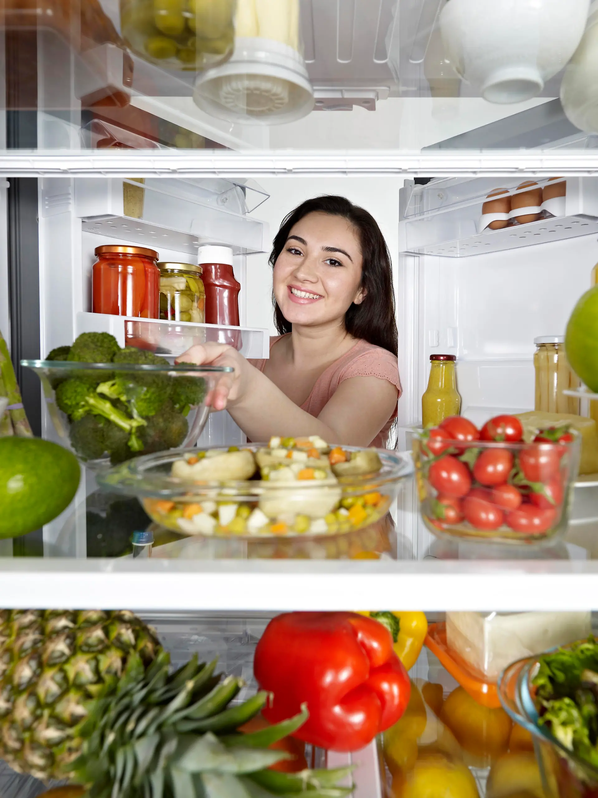 Woman looking at camera out of the fridge.