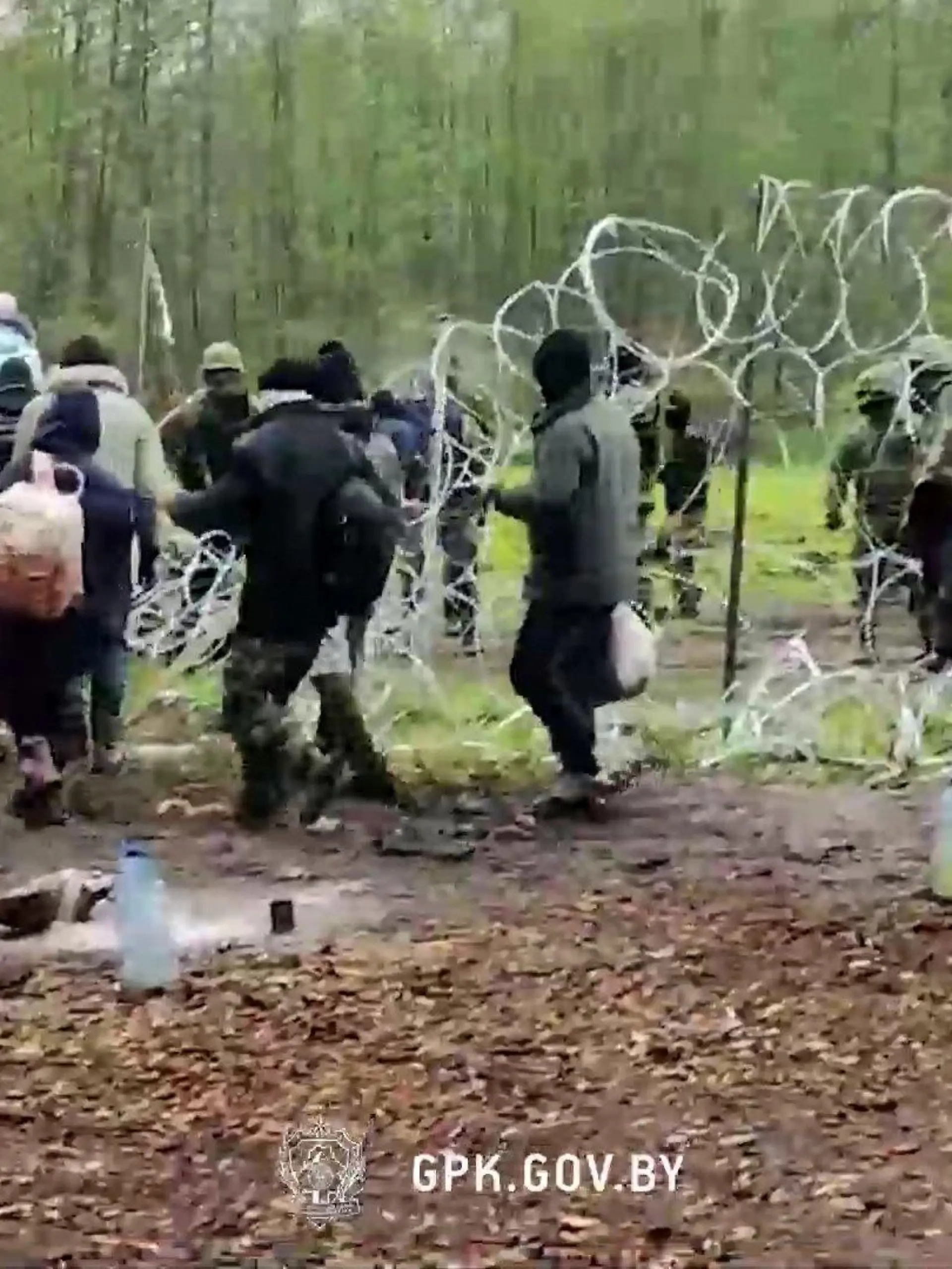Eine an der polnisch-belarussischen Grenze festsitzende Gruppe von Migranten versucht, die Grenzbarriere zu durchbrechen.