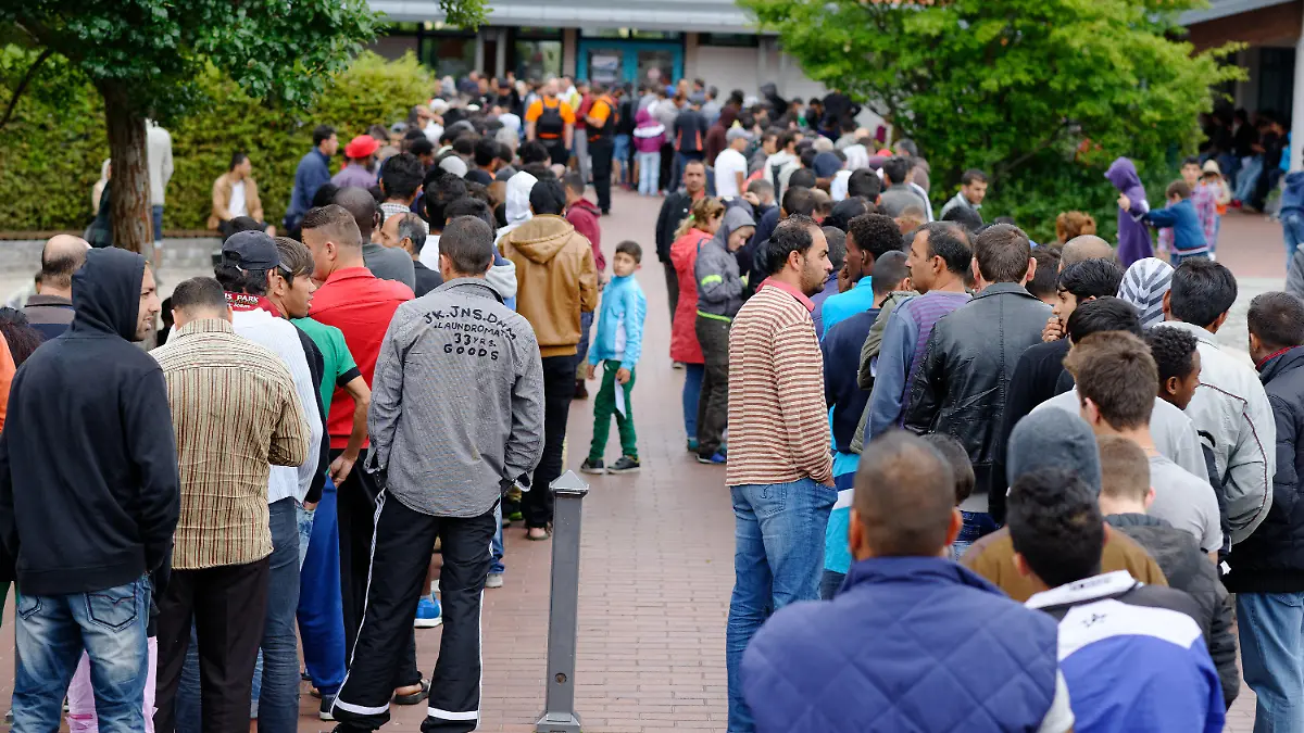 Flüchtlinge stehen am 25.08.2015 im Erstaufnahmelager für Flüchtlinge in Friedland (Niedersachsen) in einer Schlange und warten auf das Mittagessen. Das eigentlich für rund 700 Menschen konzipierte Lager im Landkreis Göttingen ist zur Zeit mit mehr als 3000 Menschen belegt. Foto: Swen Pförtner/dpa +++(c) dpa - Bildfunk+++