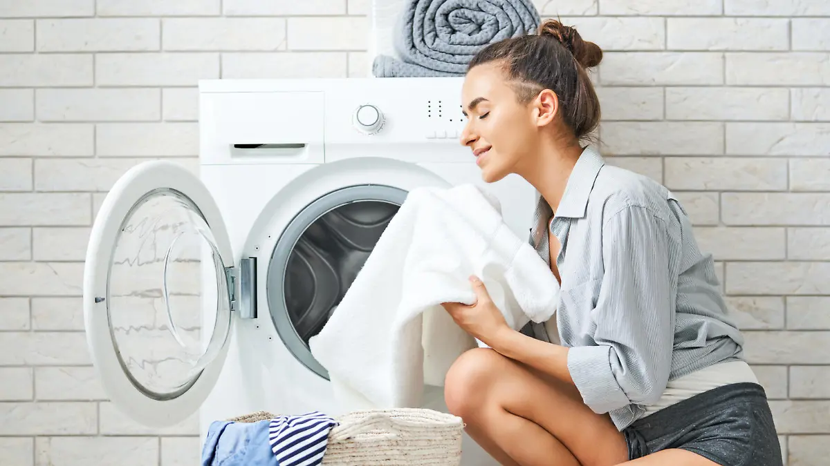 Eine Frau wäscht ihre weiße Wäsche in der Waschmaschine.