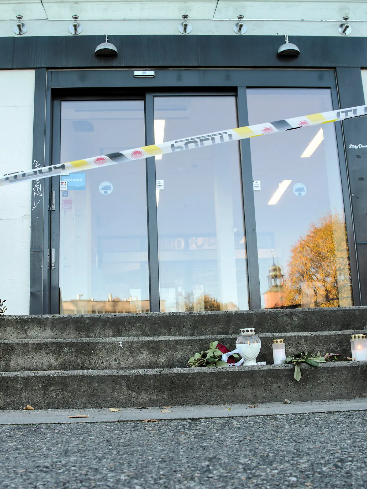 15.10.2021, Norwegen, Kongsberg: Vor einem Geschäft, das in die Gewalttat in der norwegischen Kleinstadt Kongsberg verwickelt war, stehen Blumen und Kerzen. Der Mann, der fünf Menschen getötet haben soll, wird nun von Ärzten betreut. Das sagte die Staatsanwältin der norwegischen Zeitung «Verdens Gang» am heutigen Freitag. Foto: Terje Bendiksby/NTB/AP/dpa +++ dpa-Bildfunk +++