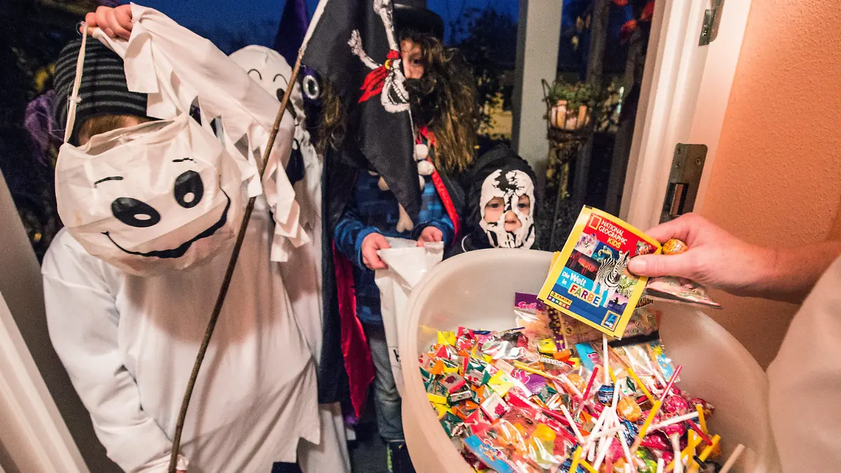 ARCHIV - 31.10.2014, Straubing: Kinder in gruseligen Kostümen bekommen an einem Hauseingang Süßigkeiten. Am 31. Oktober ist Halloween. Angesichts der Corona-Pandemie wird jedoch weiter zur Vorsicht geraten. Foto: dpa +++ dpa-Bildfunk +++