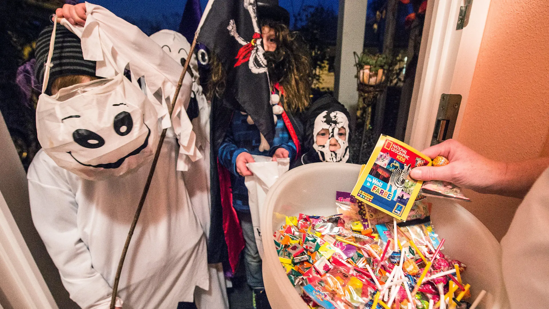 ARCHIV - 31.10.2014, Straubing: Kinder in gruseligen Kostümen bekommen an einem Hauseingang Süßigkeiten. Am 31. Oktober ist Halloween. Angesichts der Corona-Pandemie wird jedoch weiter zur Vorsicht geraten. Foto: dpa +++ dpa-Bildfunk +++