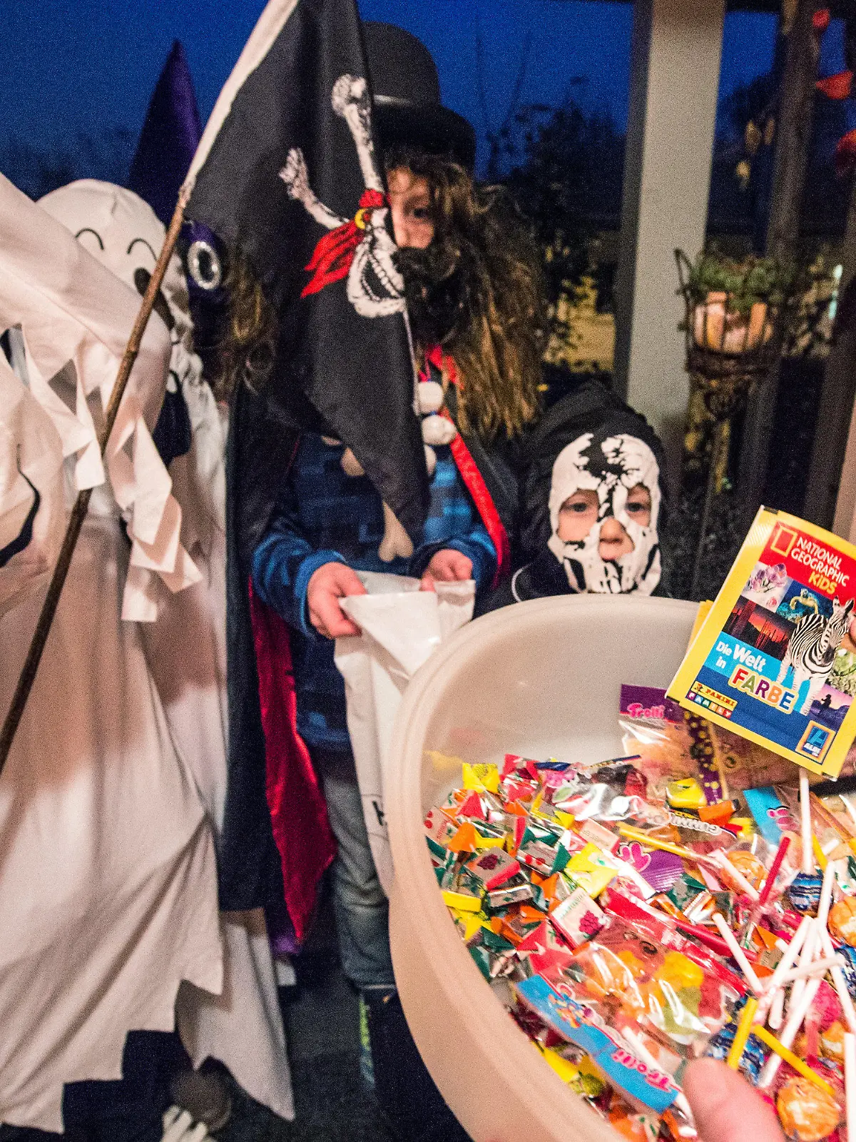 ARCHIV - 31.10.2014, Straubing: Kinder in gruseligen Kostümen bekommen an einem Hauseingang Süßigkeiten. Am 31. Oktober ist Halloween. Angesichts der Corona-Pandemie wird jedoch weiter zur Vorsicht geraten. Foto: dpa +++ dpa-Bildfunk +++