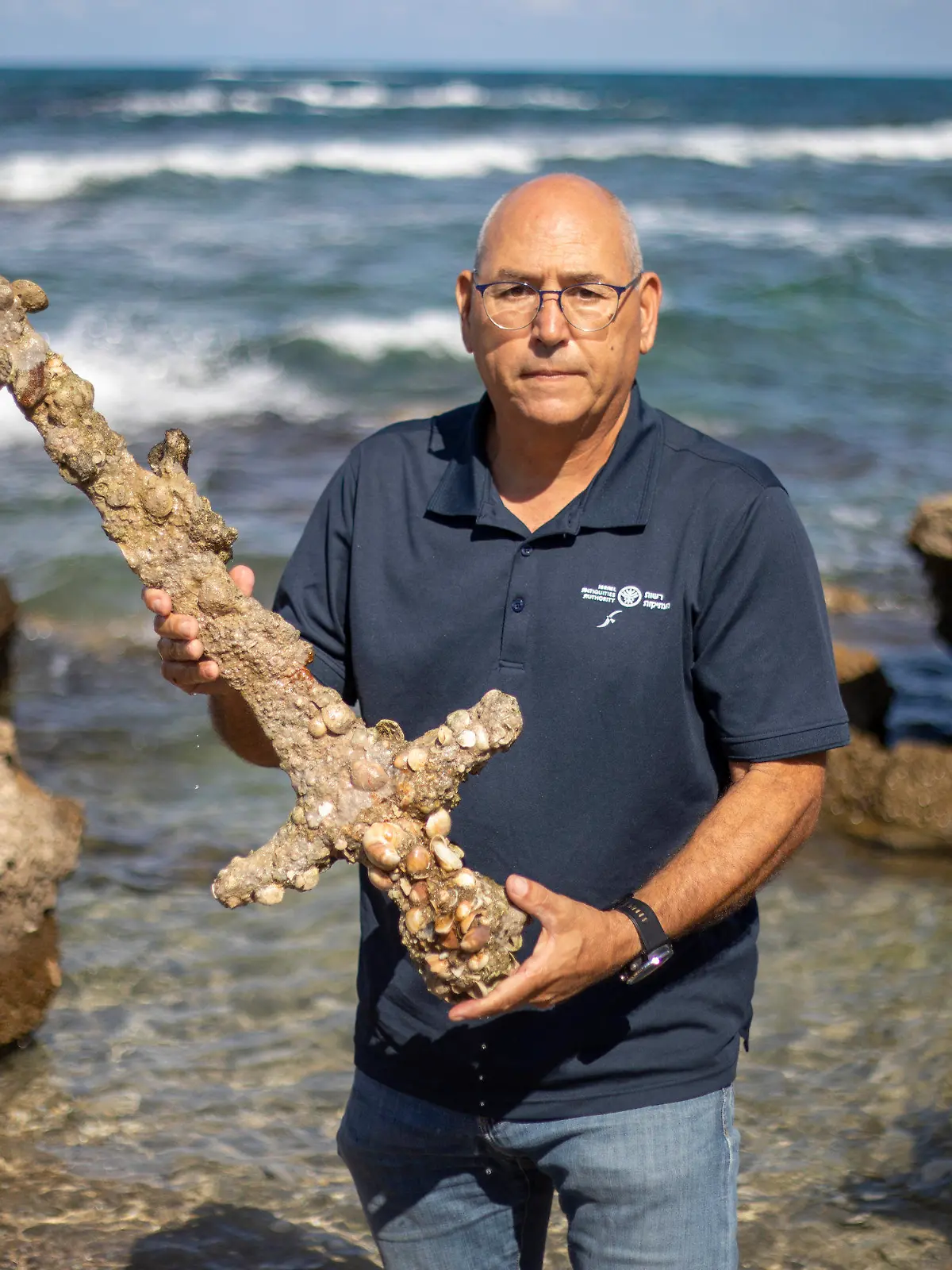 Jacob Sharvit, director of the Marine Archaeology Unit of the Israel Antiquities Authority holds a meter-long (yard-long) sword, that experts say dates back to the Crusaders is on display in Mediterranean seaport of Cesarea, Israel, Tuesday, Oct. 19, 2021. Israeli archaeologists say a scuba diver has salvaged an ancient sword off the country's Mediterranean coast that experts say dates back to the Crusaders. Israel's Antiquities Authority said Monday the man was on a weekend dive in northern Israel last Saturday when he spotted a trove of ancient artifacts that included anchors, pottery and a meter-long (yard-long) sword. Fearing the sword would be covered up by shifting sands, it says the man took it ashore and handed it over to government experts. Archaeologists believe that many ancient treasures are submerged in the area. The diver was given a certificate of appreciation for turning over the 900-year-old item. (AP Photo/Ariel Schalit)
