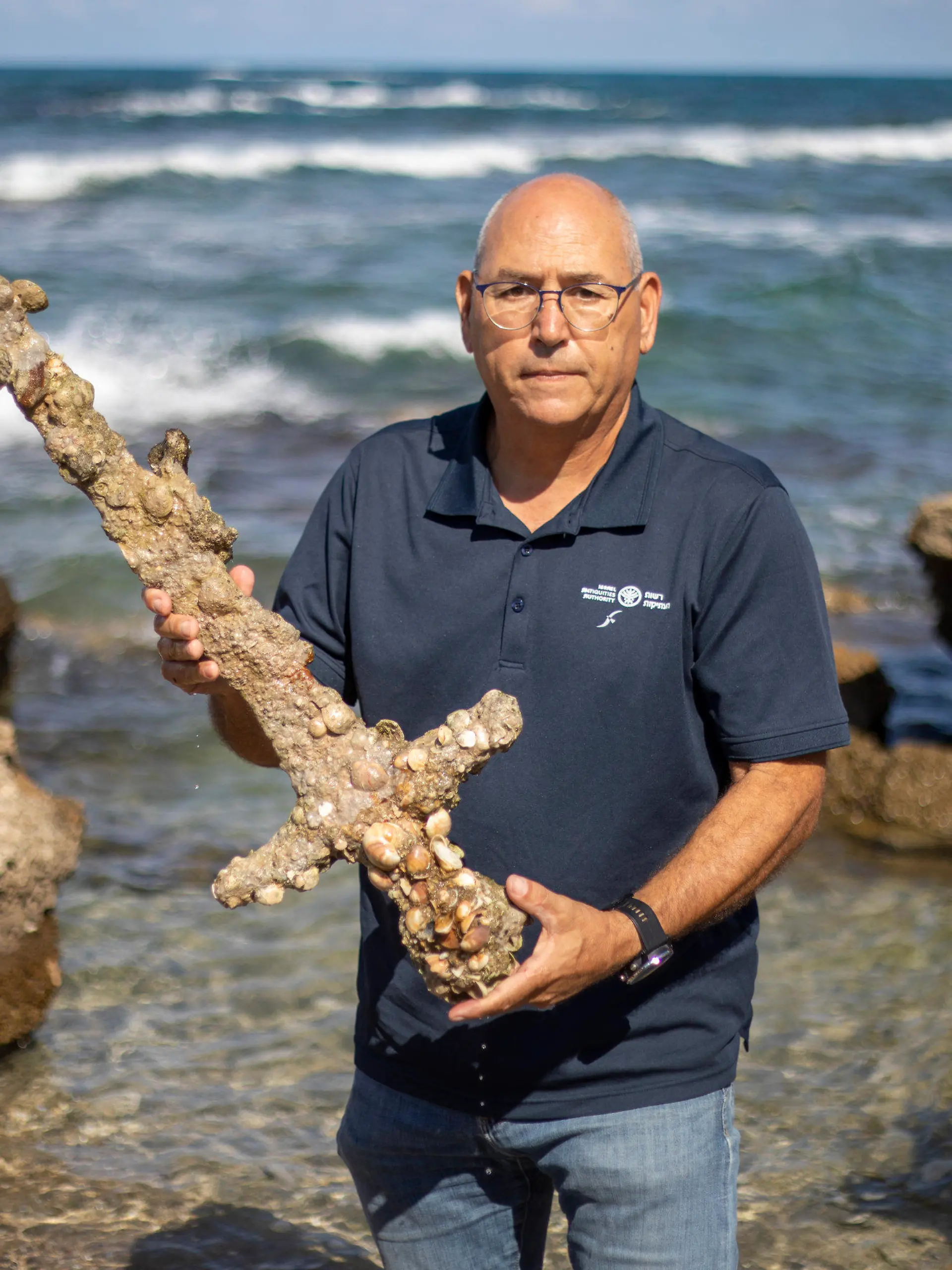 Jacob Sharvit, director of the Marine Archaeology Unit of the Israel Antiquities Authority holds a meter-long (yard-long) sword, that experts say dates back to the Crusaders is on display in Mediterranean seaport of Cesarea, Israel, Tuesday, Oct. 19, 2021. Israeli archaeologists say a scuba diver has salvaged an ancient sword off the country's Mediterranean coast that experts say dates back to the Crusaders. Israel's Antiquities Authority said Monday the man was on a weekend dive in northern Israel last Saturday when he spotted a trove of ancient artifacts that included anchors, pottery and a meter-long (yard-long) sword. Fearing the sword would be covered up by shifting sands, it says the man took it ashore and handed it over to government experts. Archaeologists believe that many ancient treasures are submerged in the area. The diver was given a certificate of appreciation for turning over the 900-year-old item. (AP Photo/Ariel Schalit)