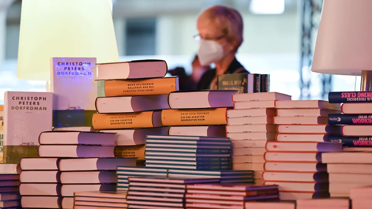 Eine Frau steht am Rande der Eröffnungspressekonferenz der Buchmesse in der Festhalle vor einem Stapel Bücher. Gastland ist in diesem Jahr Kanada.