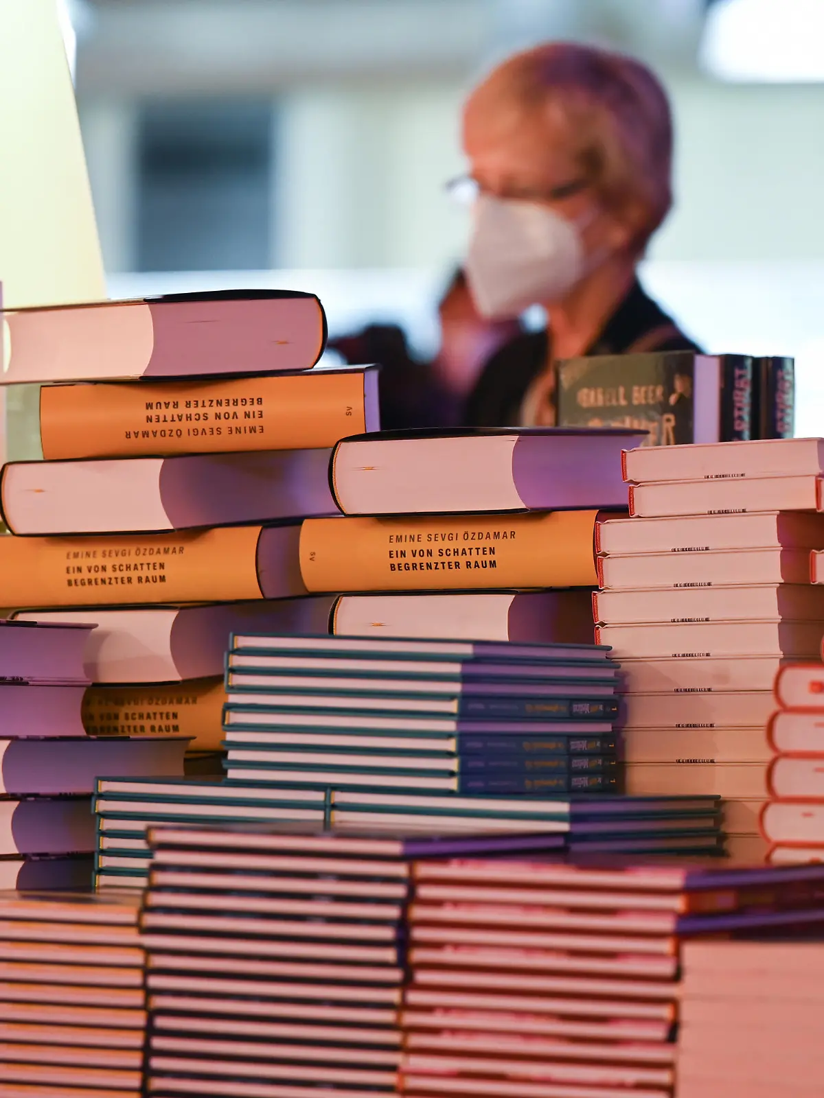Eine Frau steht am Rande der Eröffnungspressekonferenz der Buchmesse in der Festhalle vor einem Stapel Bücher. Gastland ist in diesem Jahr Kanada.
