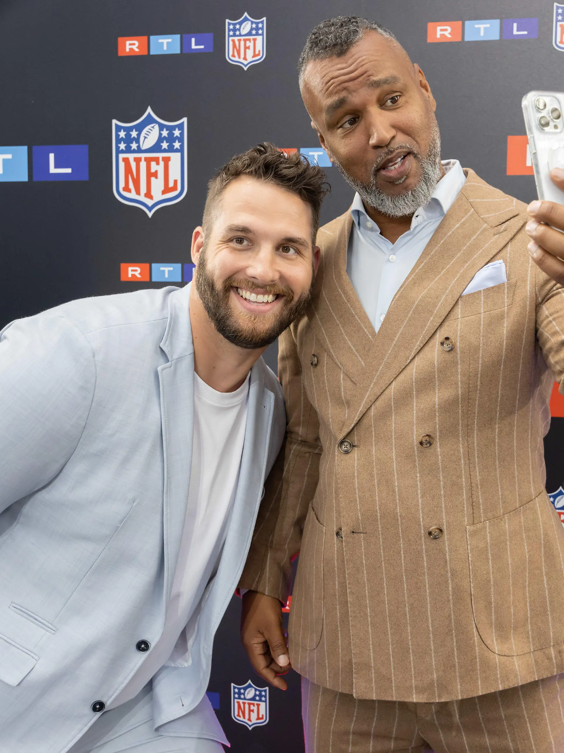 26.05.2023, Hessen, Frankfurt am Main: TV-Experte und Commissioner der European League of Football, Patrick Esume (r) und der TV-Experte und ehemaliger NFL-Spieler Björn Werner stehen an der Logowand. Beide präsentieren gemeinsam den Podcast "Football Bromance". Der neue Rechte-Inhaber RTL hat sein TV-Team und seine Planungen für die kommende NFL-Saison vorgestellt. Foto: Jürgen Kessler/dpa +++ dpa-Bildfunk +++
