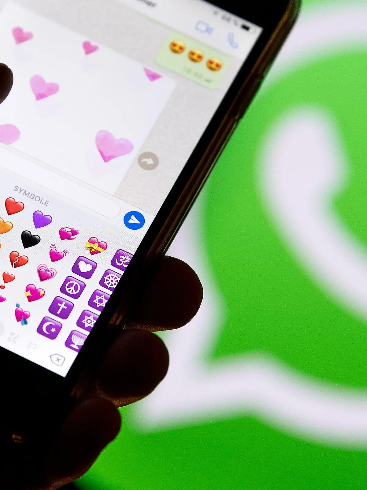ILLUSTRATION - 12.02.2018, Hessen, Frankfurt am Main: Ein Smartphone mit Emojis aus WhatsApp vor dem WhatsApp-Logo. (Zu dpa: «Liebe in Zeiten von WhatsApp - «Schatz» ist noch immer Nummer eins» vom 13.02.2018) Foto: Fabian Sommer/dpa +++ dpa-Bildfunk +++