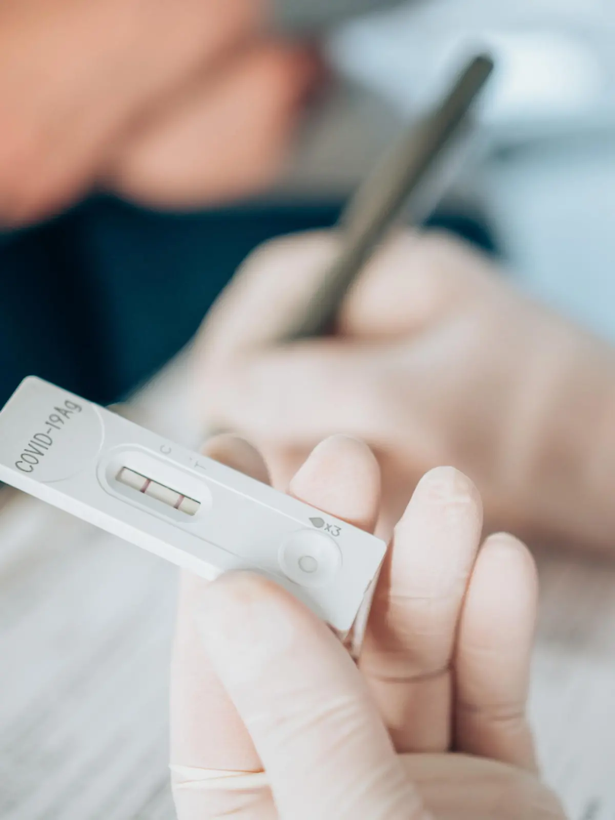 Close-up shot of doctor's hand with protective gloves holding a positive test device to senior patient. Doctor documented the result after a positive test. Doctor hand holding positive Coronavirus/Covid-19 rapid test.
