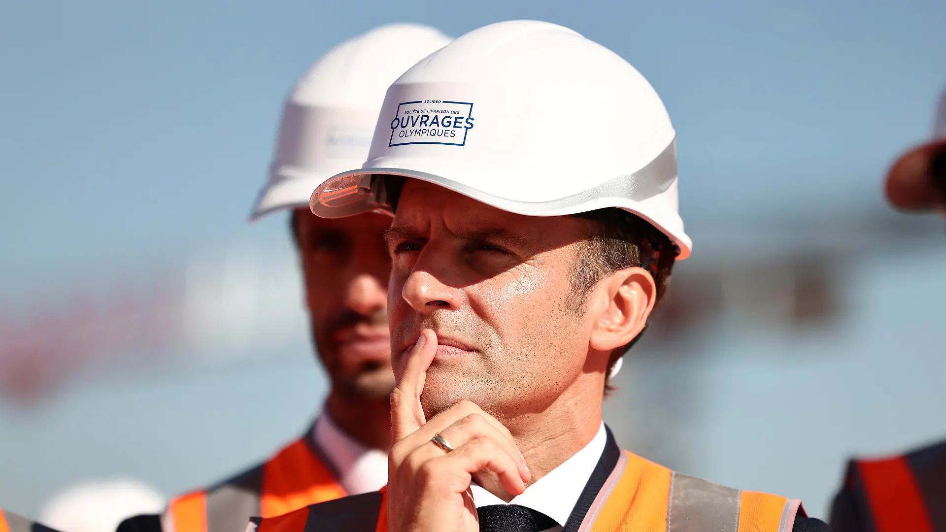 French President Emmanuel Macron, wearing a working helmet, listens to workers as he visits the building site of the Olympic Village as part of a visit to construction sites dedicated to Paris 2024 Olympic and Paralympic Games, in Paris suburb Saint-Ouen, Thursday, Oct. 14, 2021. French President Emmanuel Macron said that the government will help fund 5,000 local facilities to allow more people to practice sports, especially in the country's poorest areas, ahead of the Paris 2024 Olympics. (Sarah Meyssonnier/Pool Photo via AP)