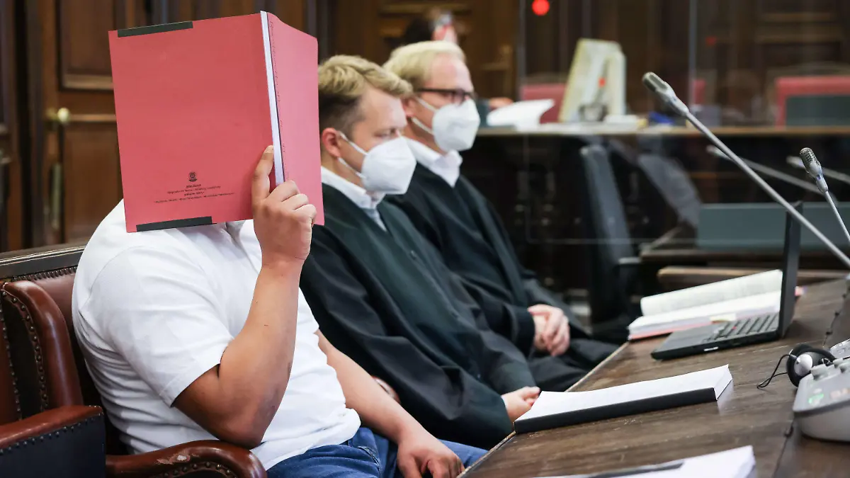 18.10.2021, Hamburg: Der Angeklagte (l) sitzt zu Beginn des Prozesses neben seinen Anwälten Dennis Dördrechter (M) und Christian Denzel im Gerichtssaal im Strafjustizgebäude. Der 23-Jährige muss sich wegen Totschlags vor dem Landgericht Hamburg verantworten. Er soll im Fahrradkeller eines Wohnhauses eine junge Frau getötet haben. Foto: Christian Charisius/dpa/Pool/dpa +++ dpa-Bildfunk +++
