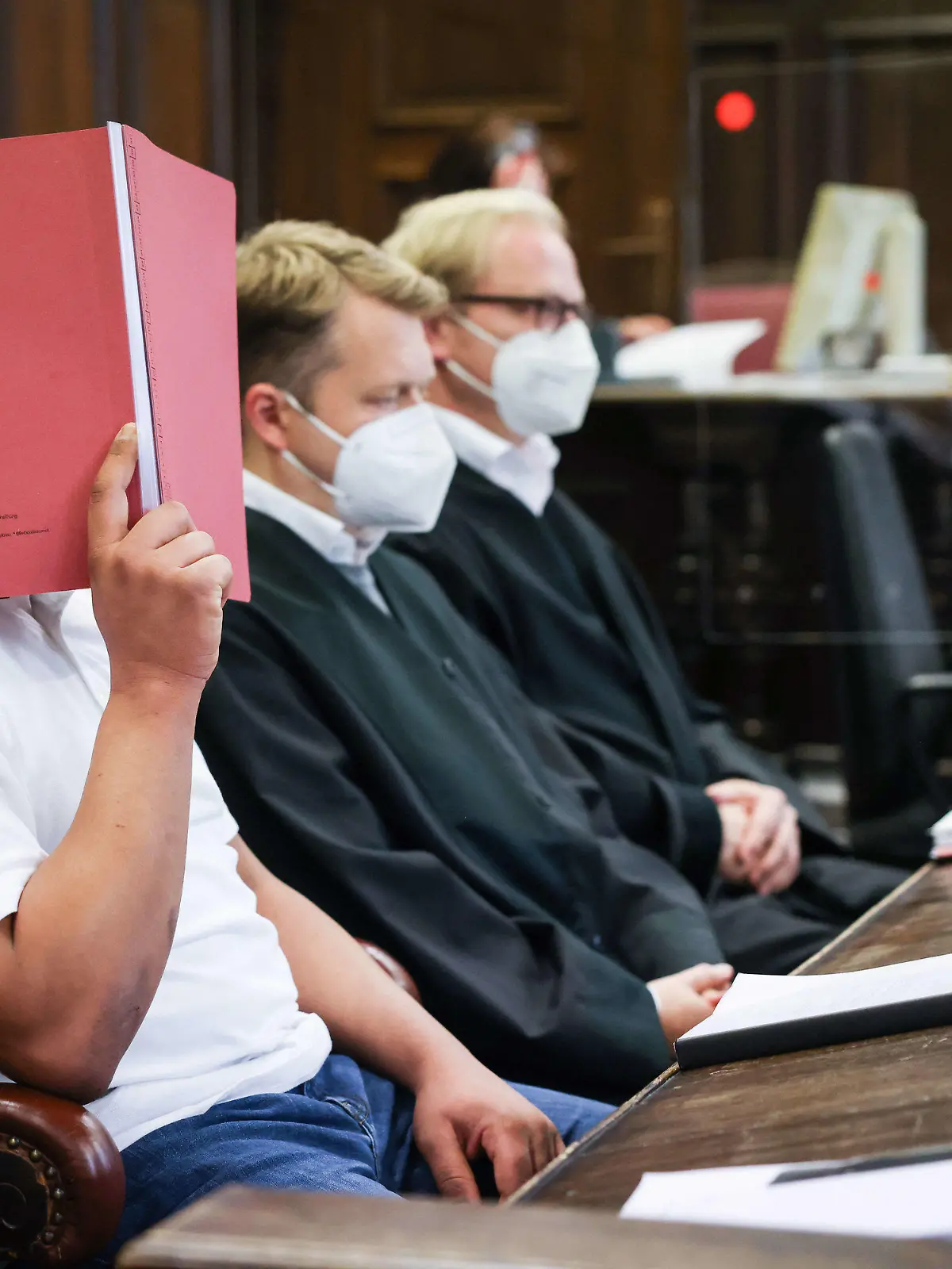 18.10.2021, Hamburg: Der Angeklagte (l) sitzt zu Beginn des Prozesses neben seinen Anwälten Dennis Dördrechter (M) und Christian Denzel im Gerichtssaal im Strafjustizgebäude. Der 23-Jährige muss sich wegen Totschlags vor dem Landgericht Hamburg verantworten. Er soll im Fahrradkeller eines Wohnhauses eine junge Frau getötet haben. Foto: Christian Charisius/dpa/Pool/dpa +++ dpa-Bildfunk +++