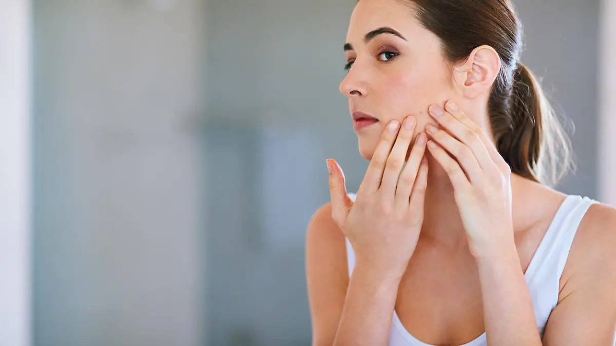 Cropped shot of a young woman squeezing a pimple on her face