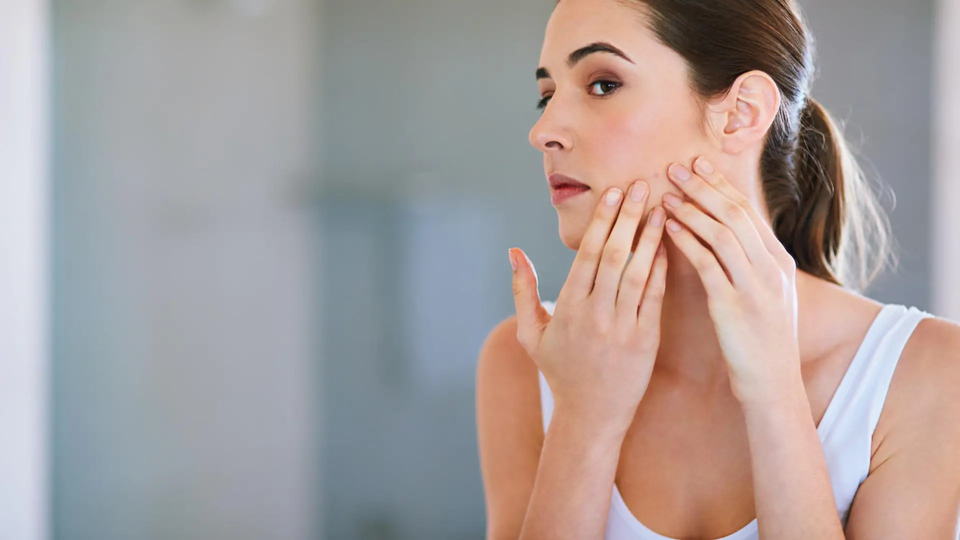 Cropped shot of a young woman squeezing a pimple on her face
