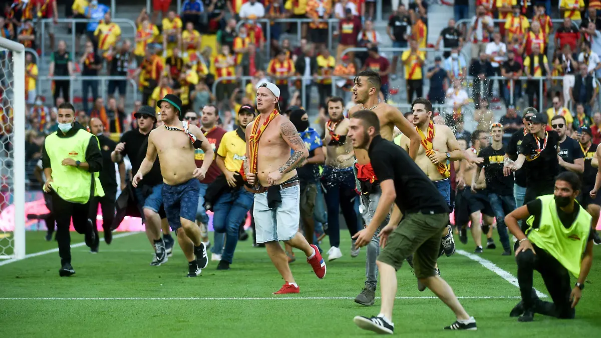 18.09.2021, Frankreich, Lens: Fußball: Ligue 1, Frankreich, RC Lens - OSC Lille. Fans des RC Lens stürmen das Spielfeld während des Spiels. Beim Erstliga-Spiel zwischen RC Lens und Fußball-Meister OSC Lille haben Fans beider Clubs das Spielfeld gestürmt und sich Handgemenge geliefert. Foto: Francois Lo Presti/AFP/dpa +++ dpa-Bildfunk +++