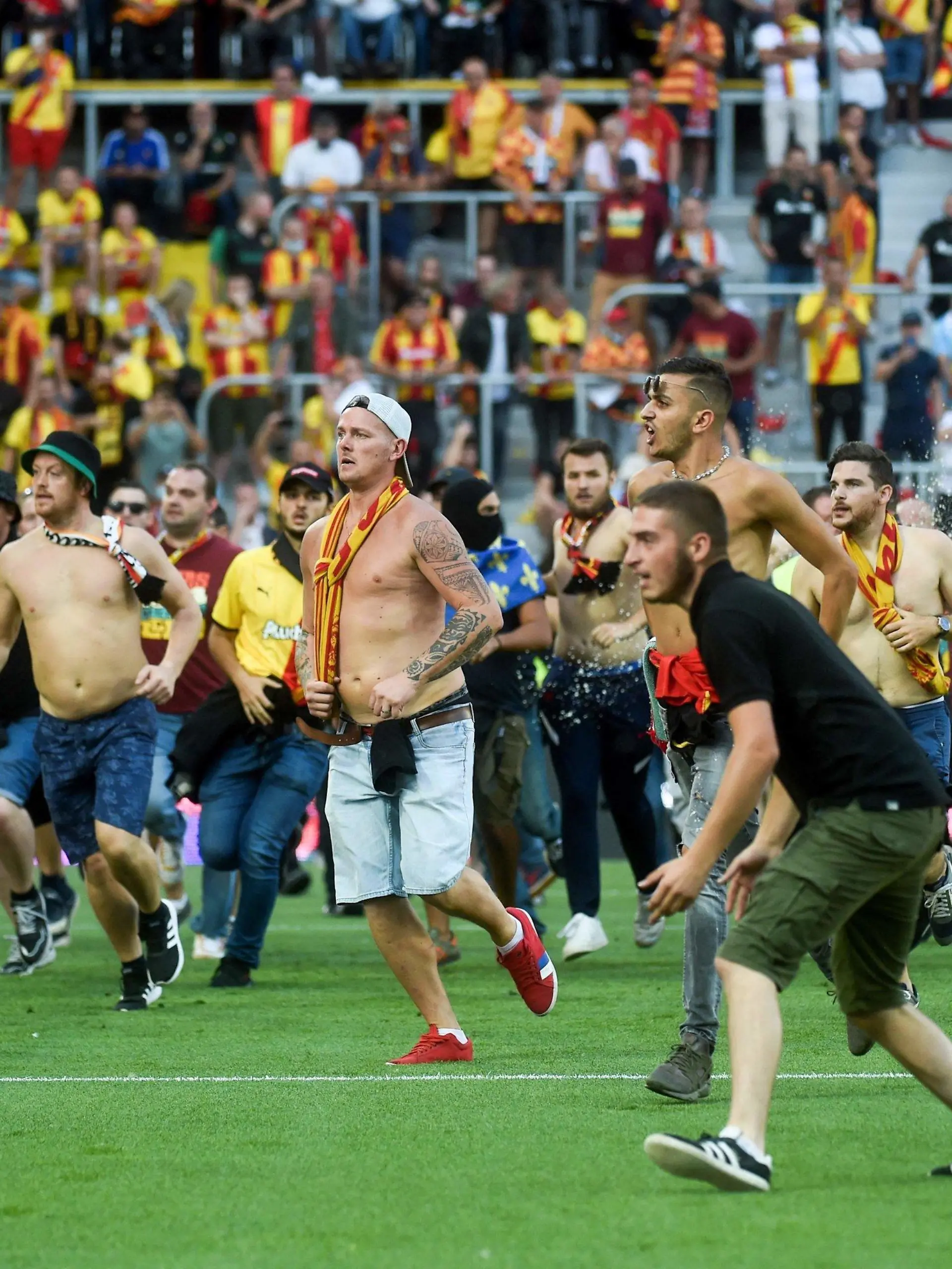 18.09.2021, Frankreich, Lens: Fußball: Ligue 1, Frankreich, RC Lens - OSC Lille. Fans des RC Lens stürmen das Spielfeld während des Spiels. Beim Erstliga-Spiel zwischen RC Lens und Fußball-Meister OSC Lille haben Fans beider Clubs das Spielfeld gestürmt und sich Handgemenge geliefert. Foto: Francois Lo Presti/AFP/dpa +++ dpa-Bildfunk +++