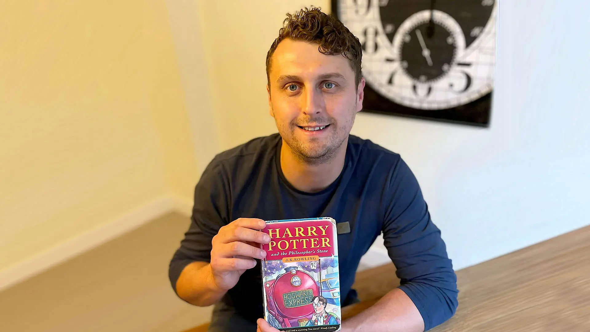 Harry Potter (33) aus Großbitannien sitzt an einem Tisch und hält die Erstauflage in den Händen.