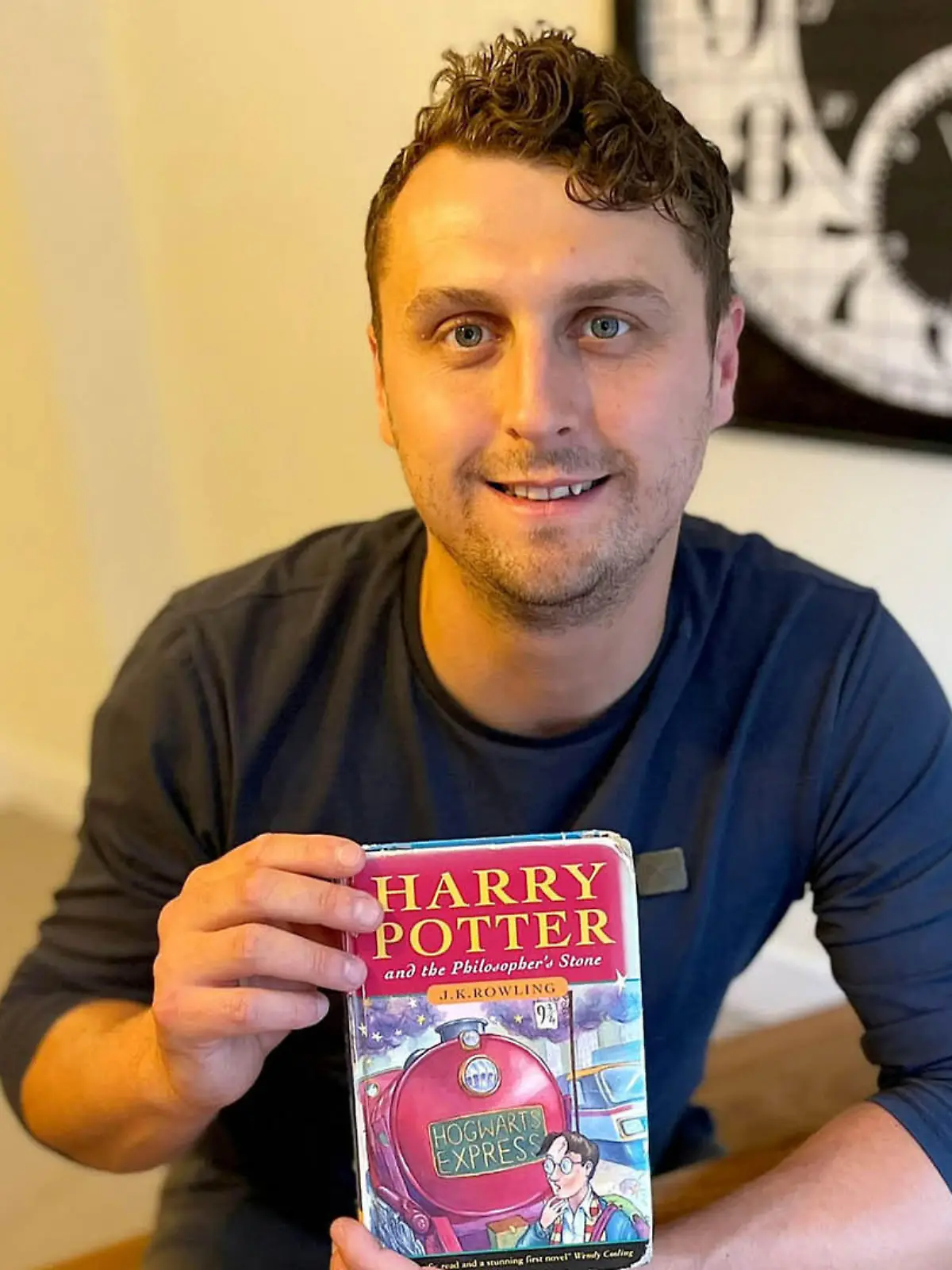 Harry Potter (33) aus Großbitannien sitzt an einem Tisch und hält die Erstauflage in den Händen.