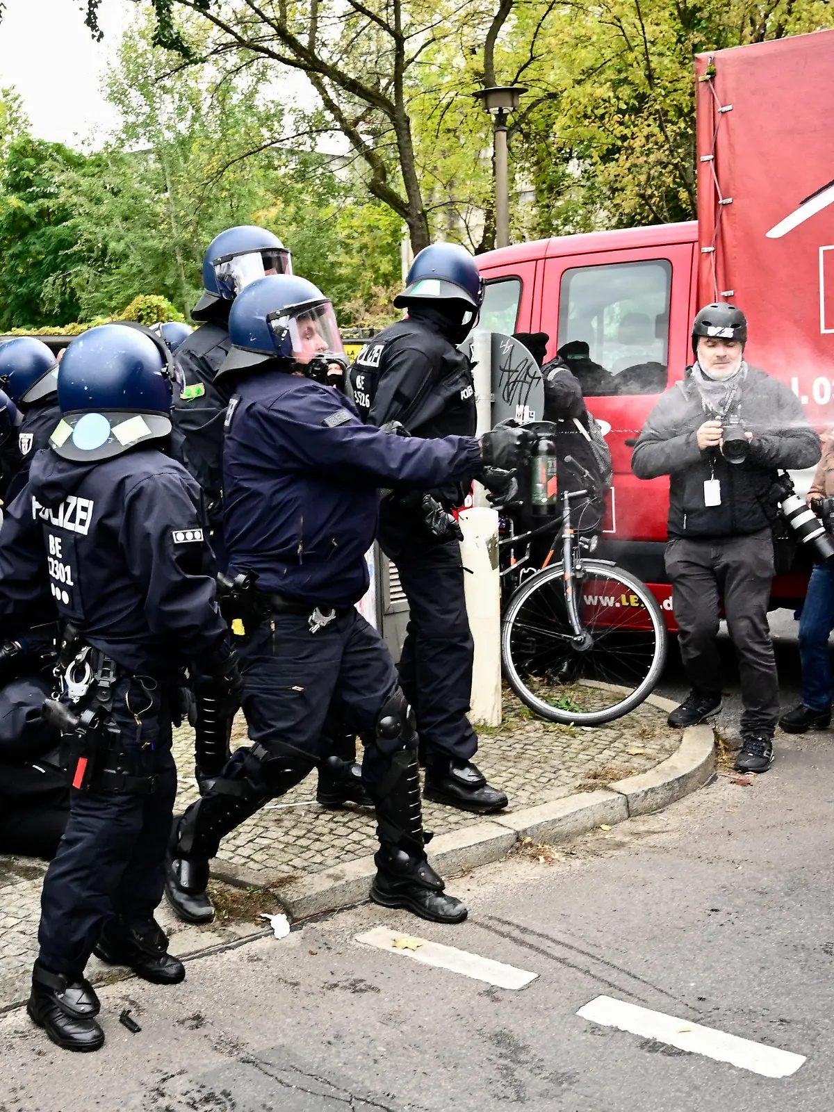 dpatopbilder - 15.10.2021, Berlin: Ein Polizist sprüht während einer Verhaftung eines Demonstranten am Rande der Räumung der Bauwagensiedlung Pfefferspray. Die sogenannte Wagenburg «Köpi» gilt seit vielen Jahren als eines der Symbolprojekte der linksradikalen Szene in Berlin. Foto: Fabian Sommer/dpa +++ dpa-Bildfunk +++