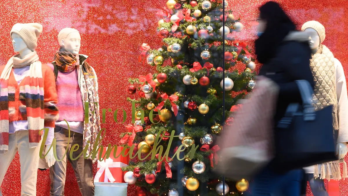 ARCHIV - 08.12.2020, Sachsen, Dresden: Eine Passantin geht mit einer Papiertüte auf der Einkaufsstraße Prager Straße vor einem Schaufenster mit der Aufschrift «Frohe Weihnachten» entlang. Die Suche nach dem passenden Weihnachtsgeschenk könnte in diesem Jahr noch etwas mühsamer werden als sonst - besonders wenn es um Elektronik geht. (zu dpa «Die Suche nach dem Weihnachtsgeschenk könnte schwierig werden») Foto: Sebastian Kahnert/dpa-Zentralbild/dpa +++ dpa-Bildfunk +++