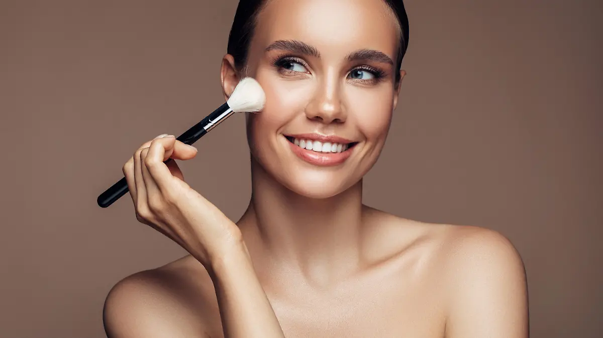 Beautiful young woman applying foundation powder