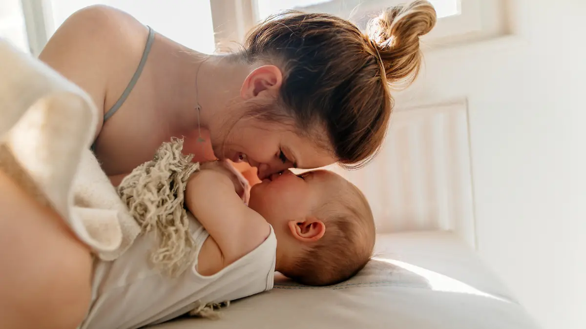 Mom and baby boy cuddling on the bed in the morning