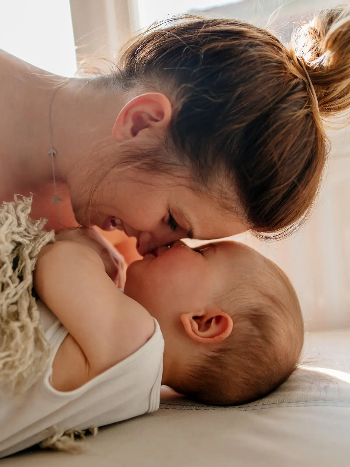 Mom and baby boy cuddling on the bed in the morning