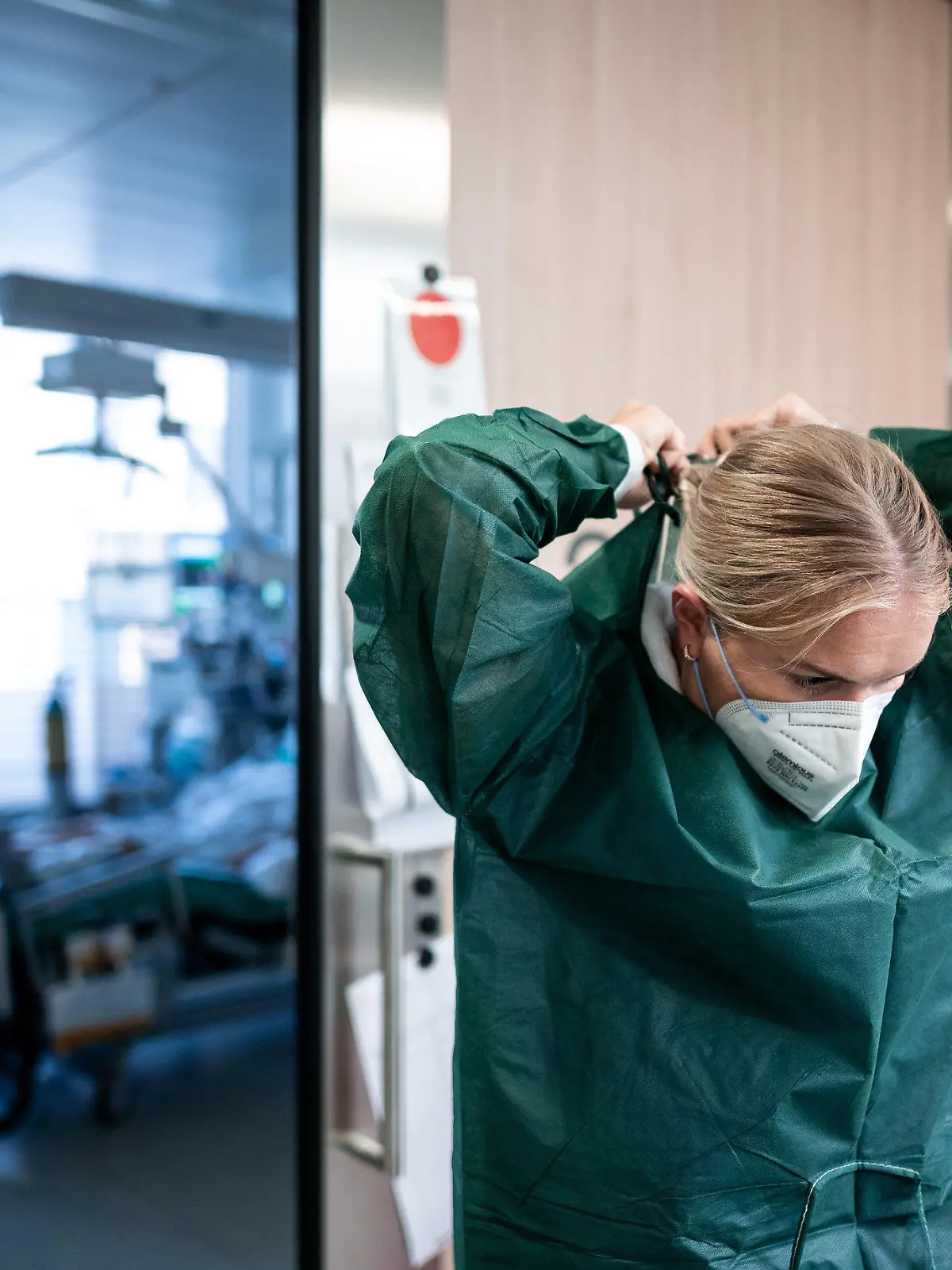 23.09.2021, Nordrhein-Westfalen, Essen: Josephin Kampmann, Gesundheits- und Krankenpflegerin, steht auf dem Gang der Corona-Intensivstation des Universitätsklinikums Essen und zieht Schutzkleidung an. Patienten mit Corona-Infektion werden auf der Intensivstation IT2 im Operativen Zentrum II des Universitätsklinikum Essen behandelt. Foto: Fabian Strauch/dpa +++ dpa-Bildfunk +++