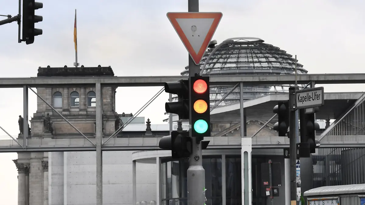 27.09.2021, Berlin: Eine Ampel, an der für einen Moment die Farben Rot, Gelb und Grün gleichzeitig leuchten, ist am Tag nach der Bundestagswahl im Regierungsviertel vor der Kuppel des Reichstagsgebäudes, dem Sitz des Bundestags, zu sehen. Foto: Julian Stratenschulte/dpa +++ dpa-Bildfunk +++