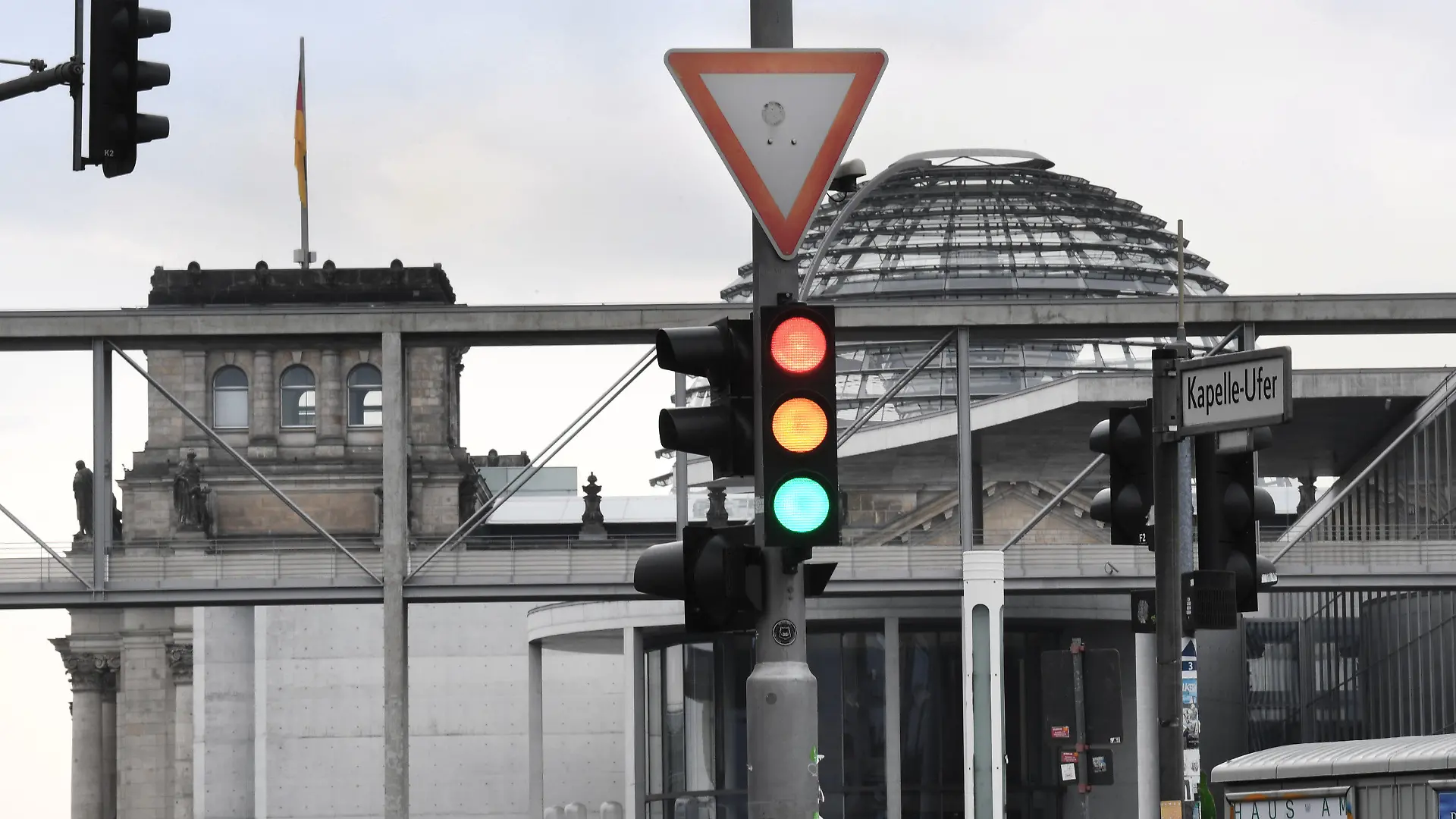 27.09.2021, Berlin: Eine Ampel, an der für einen Moment die Farben Rot, Gelb und Grün gleichzeitig leuchten, ist am Tag nach der Bundestagswahl im Regierungsviertel vor der Kuppel des Reichstagsgebäudes, dem Sitz des Bundestags, zu sehen. Foto: Julian Stratenschulte/dpa +++ dpa-Bildfunk +++
