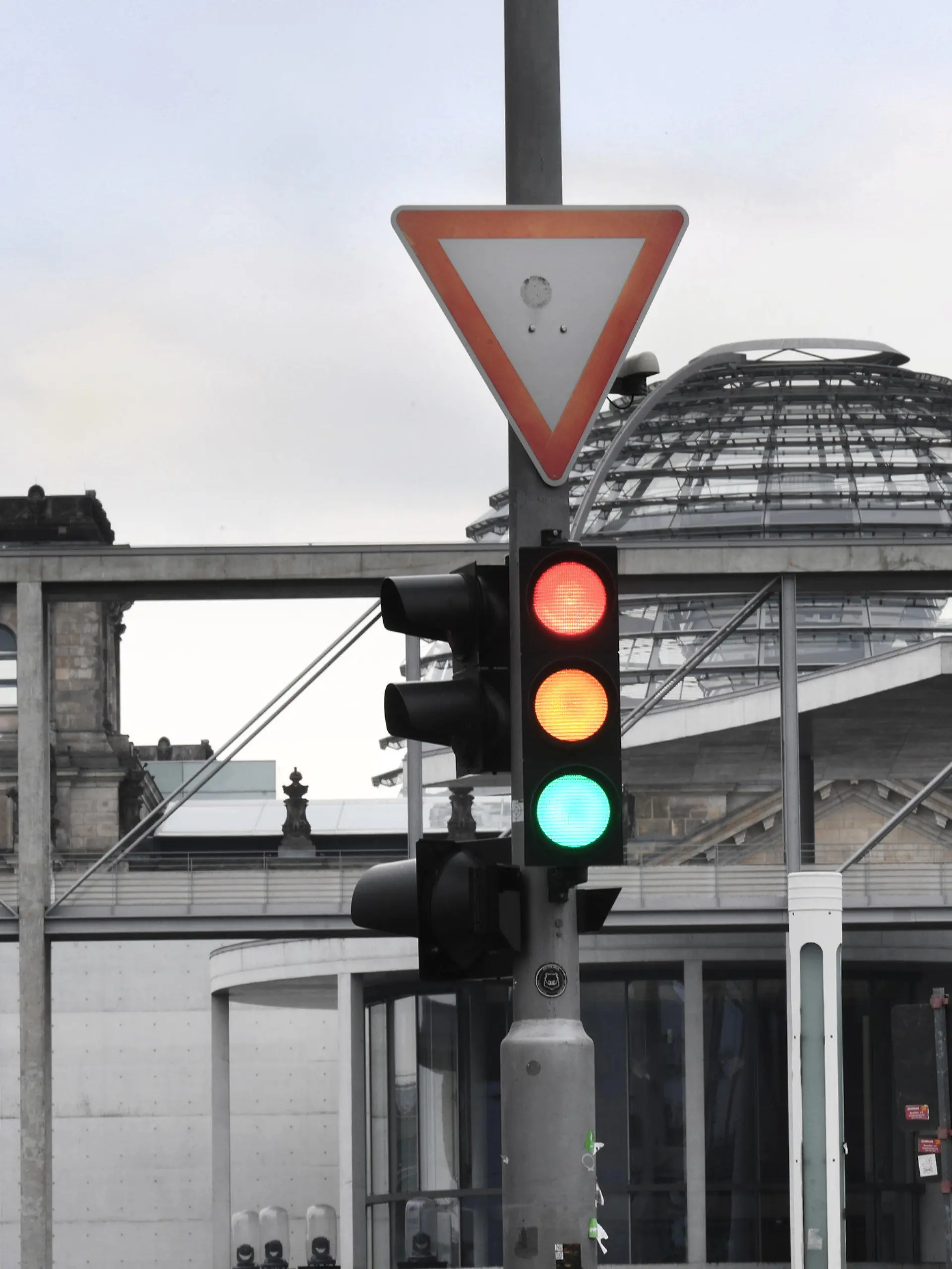 27.09.2021, Berlin: Eine Ampel, an der für einen Moment die Farben Rot, Gelb und Grün gleichzeitig leuchten, ist am Tag nach der Bundestagswahl im Regierungsviertel vor der Kuppel des Reichstagsgebäudes, dem Sitz des Bundestags, zu sehen. Foto: Julian Stratenschulte/dpa +++ dpa-Bildfunk +++