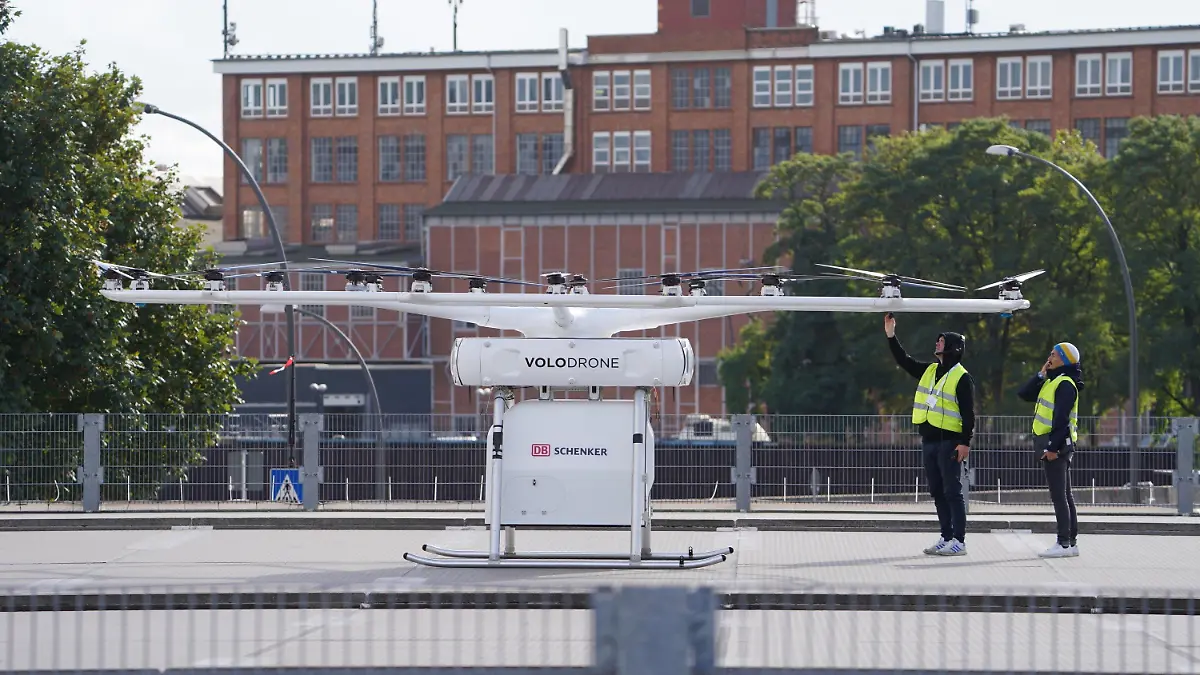 12.10.2021, Hamburg: Zwei Techniker stehen vor dem Start im Hafen vor der Schwerlastdrohne Volodrone. Erstmals soll in Hamburg eine Schwerlastdrohne fliegen. Für eine Woche ist die Hansestadt das weltweite Schaufenster für intelligente Verkehrssysteme. Zum ITS-Weltkongress treffen sich Experten für Verkehr, Logistik und Digitalisierung in Hamburg, um darüber zu diskutieren, wie gewerblicher und privater Verkehr unter den Vorzeichen von Klimakrise und steigenden Mobilitätswünschen aussehen könnten. Foto: Marcus Brandt/dpa +++ dpa-Bildfunk +++