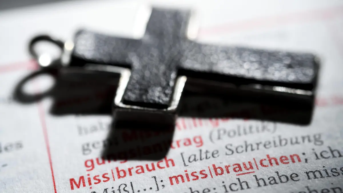 Kreuz auf einem Wörterbuch mit dem Wort Missbrauch, Symbolfoto Missbrauchsskandal *** Cross on a dictionary with the word abuse symbol photo abuse scandal