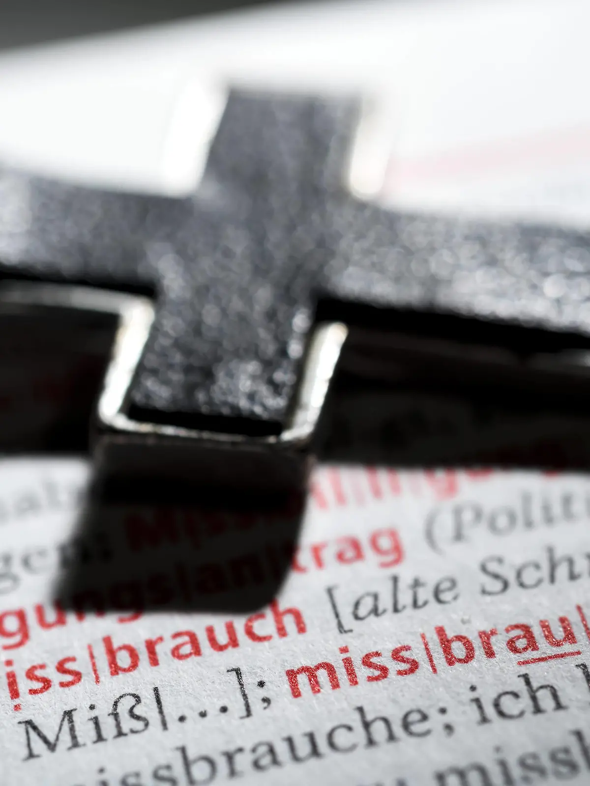 Kreuz auf einem Wörterbuch mit dem Wort Missbrauch, Symbolfoto Missbrauchsskandal *** Cross on a dictionary with the word abuse symbol photo abuse scandal  