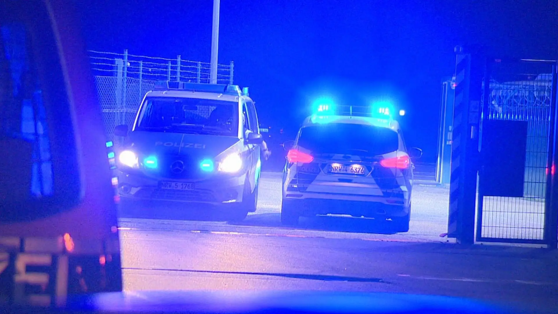 10.10.2021, Nordrhein-Westfalen, Weeze: Polizisten passieren in Polizeifahrzeugen ein Tor am Flughafen Weeze. Ein Auto hat am Flughafen Weeze am Niederrhein einen Zaun in der Nähe der Rollbahn durchbrochen, so dass eine Passagiermaschine ihren Landeanflug abbrechen musste. Foto: Guido Schulmann/tv-niederrhein/dpa +++ dpa-Bildfunk +++