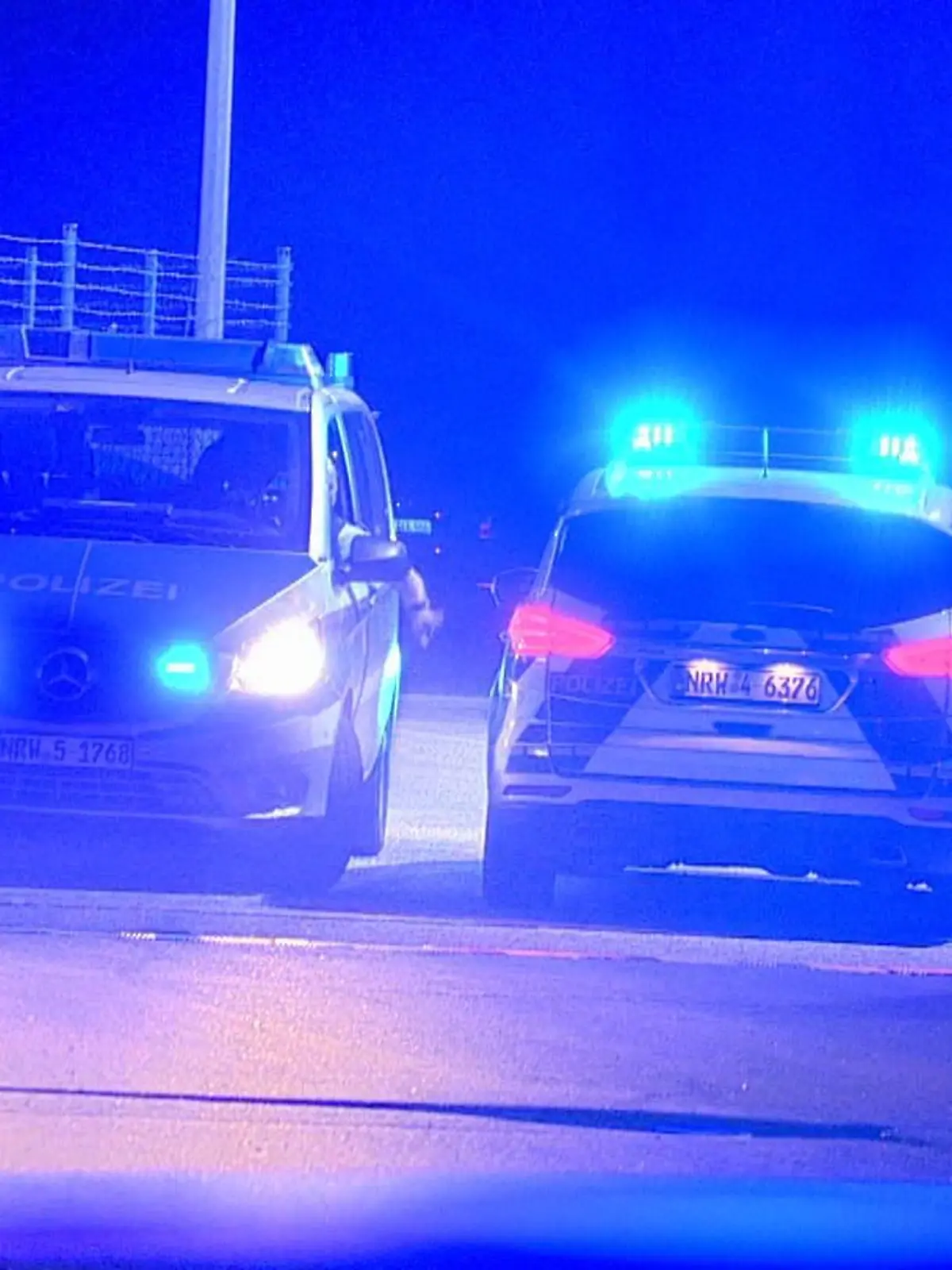 10.10.2021, Nordrhein-Westfalen, Weeze: Polizisten passieren in Polizeifahrzeugen ein Tor am Flughafen Weeze. Ein Auto hat am Flughafen Weeze am Niederrhein einen Zaun in der Nähe der Rollbahn durchbrochen, so dass eine Passagiermaschine ihren Landeanflug abbrechen musste. Foto: Guido Schulmann/tv-niederrhein/dpa +++ dpa-Bildfunk +++