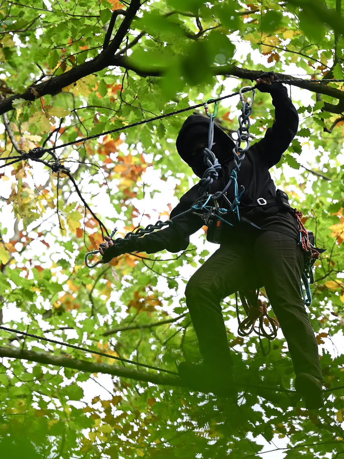 dpatopbilder - 07.10.2021, Hessen, Frankfurt/Main: Eine Aktivistin bewegt sich in einem Wald am Teufelsbruch im Osten der Stadt an Seilen zwischen den Bäumen. Umweltaktivisten protestieren mit einer Waldbesetzung gegen die für den Riederwaldtunnel geplante Rodung des Waldes. Dafür haben sie Baumplattformen in bis zu 15 Metern Höhe errichtet. In der Zeit vom 1. Oktober 2021 bis 28. Februar 2022 sollen alle Bäume im Trassenbereich der A66 im Fechenheimer Wald, im Erlenbruch und im Teufelsbruch gefällt werden. Foto: Arne Dedert/dpa +++ dpa-Bildfunk +++