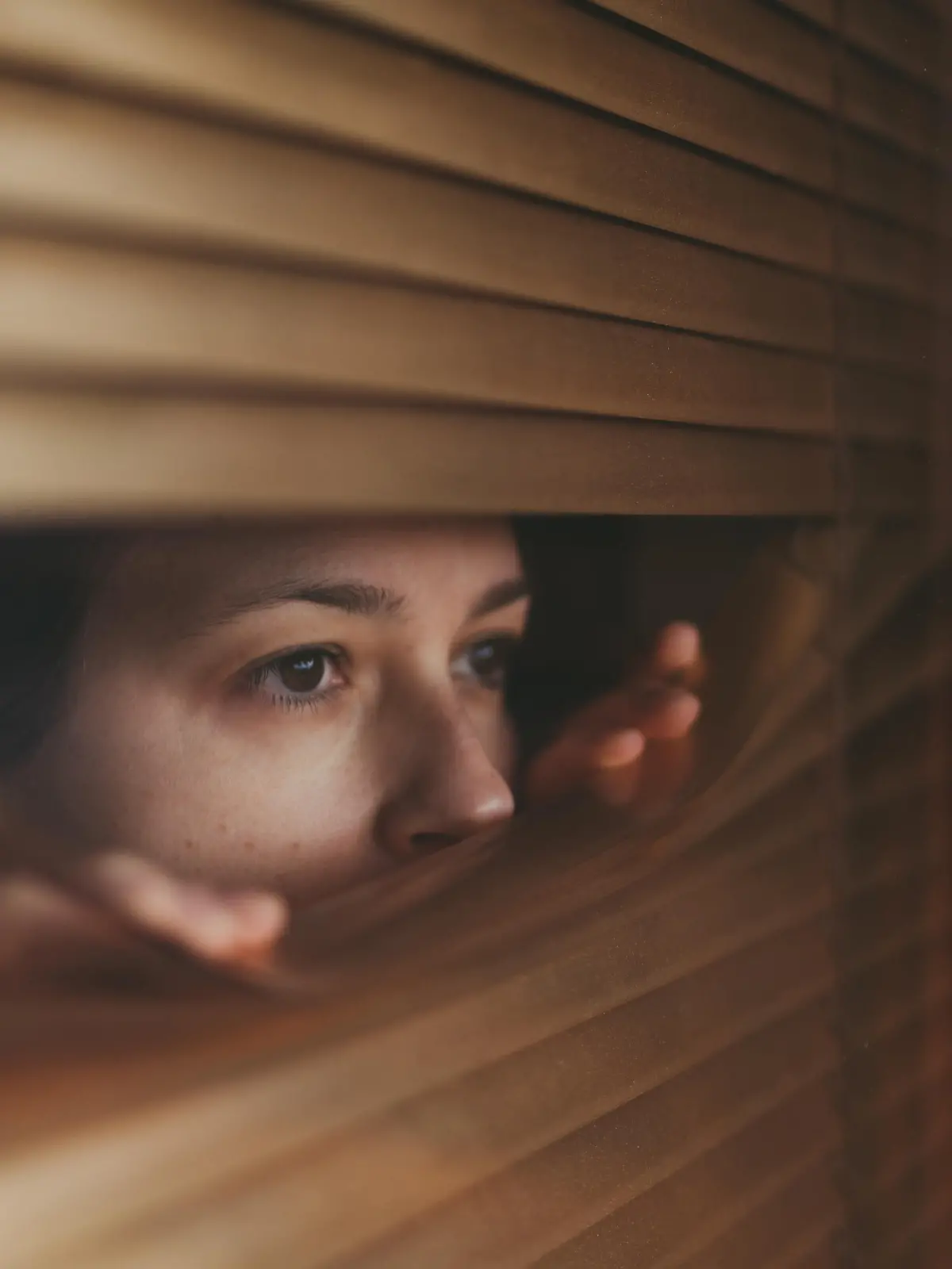Woman at home during COVID-19 pandemic is looking through window