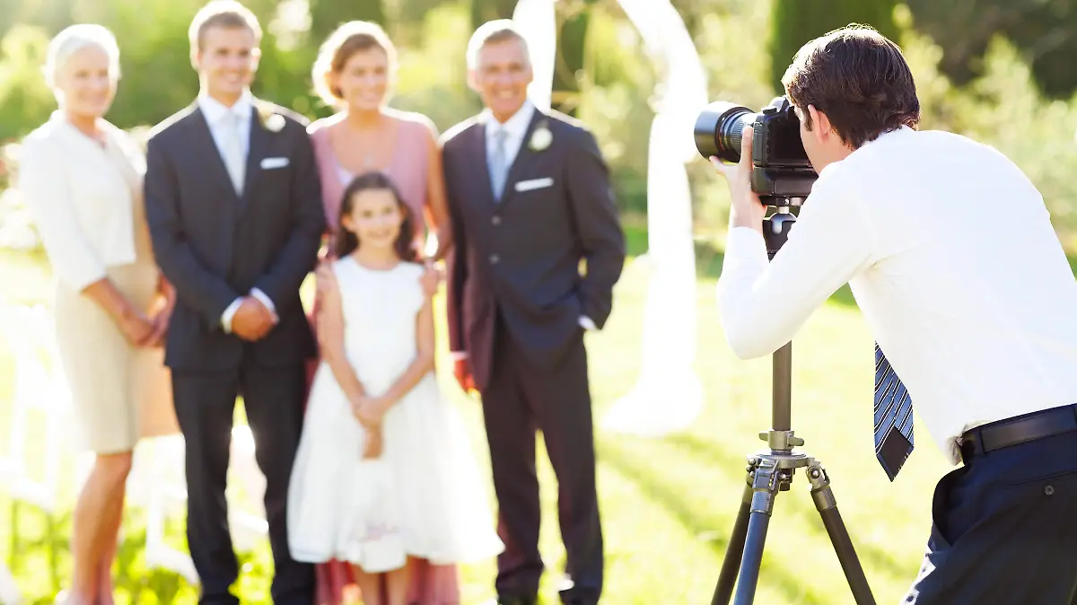 Young man photographing family at outdoor wedding. Horizontal shot.