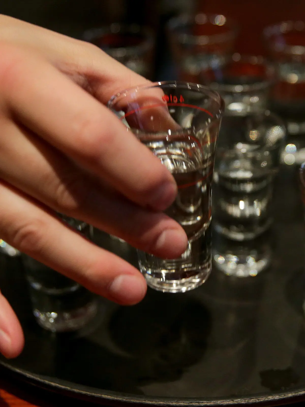 ILLUSTRATION - Eine Hand greift am 05.10.2015 in einer Gaststätte in Hamburg nach einem der gefüllten Schnapsgläser auf einem Tablett. Deutschlands geltende Altersfreigaben für Alkohol sind einer Mehrheit in Deutschland laut einer Umfrage zu lasch. In einer repräsentativen Befragung des Meinungsforschungsinstituts YouGov sprachen sich 54 Prozent dafür aus, erst 18-Jährigen den Genuss von Wein und Sekt zu erlauben. 25 Prozent der Befragten nannten das derzeit geltende Mindestalter von 16 Jahren. Foto: Axel Heimken/dpa  (zu dpa "Umfrage: Mehrheit für strengere Alkohol-Altersfreigaben" am 29.10.2015) +++(c) dpa - Bildfunk+++