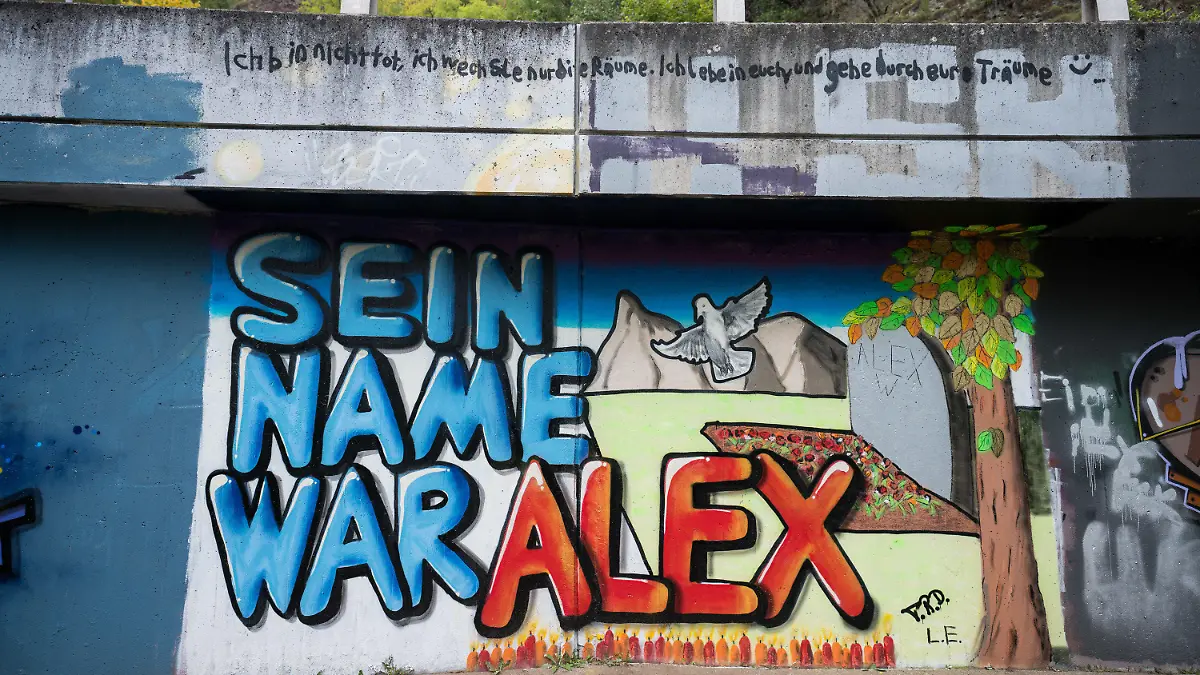 07.10.2021, Rheinland-Pfalz, Idar-Oberstein: Auf einer Mauer entlang der Nahe ist ein Graffiti "Sein Name war Alex" für getöteten Tankstellen-Mitarbeiter gemalt. Ein Mitarbeiter der Tankstelle war am 18. September von einem Mann erschossen worden. Das Opfer hatte den Kunden auf die Maskenpflicht hingewiesen, da dieser ohne Maske Bier kaufen wollte. Foto: Oliver Dietze/dpa - ACHTUNG: Nur zur redaktionellen Verwendung und nur mit vollständiger Nennung des vorstehenden Credits +++ dpa-Bildfunk +++