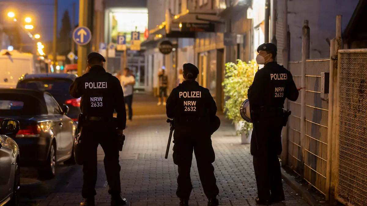 16.08.2020, Nordrhein-Westfalen, Duisburg: Drei Polizeikräfte stehen während einer Razzia an der Weseler Straße. Die nordrhein-westfälische Polizei und mehrere Behörden sind am Samstagabend in acht Städten gegen Clankriminalität vorgegangen. In Essen wurden Wettbüros und Spielautomaten-Geschäfte unter die Lupe genommen. Auch Kulturvereine und Teestuben wurden durchsucht. Foto: Christoph Reichwein (crei)/dpa +++ dpa-Bildfunk +++